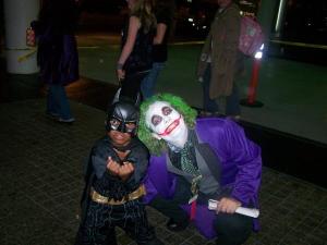 A child dressed as Batman poses with an adult in a Joker costume at a convention.