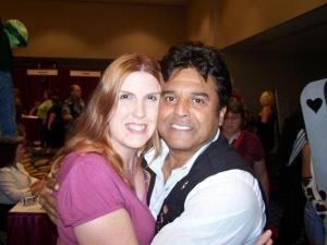 A woman and Erik Estrada embrace and smile at DragonCon, surrounded by a convention atmosphere.