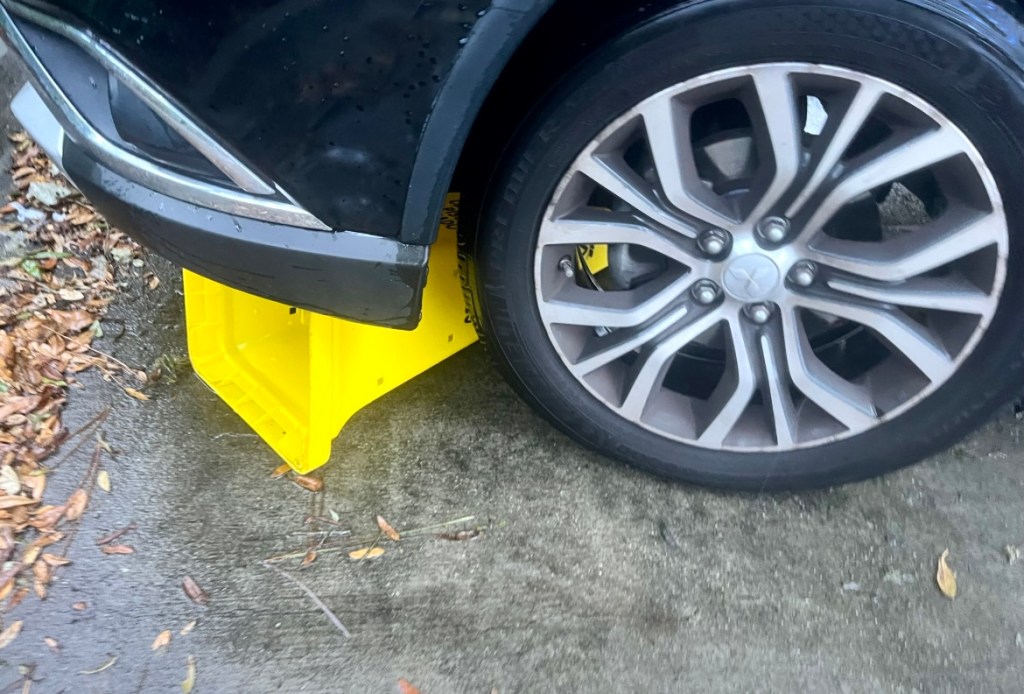 A black car with a parking cone under tire