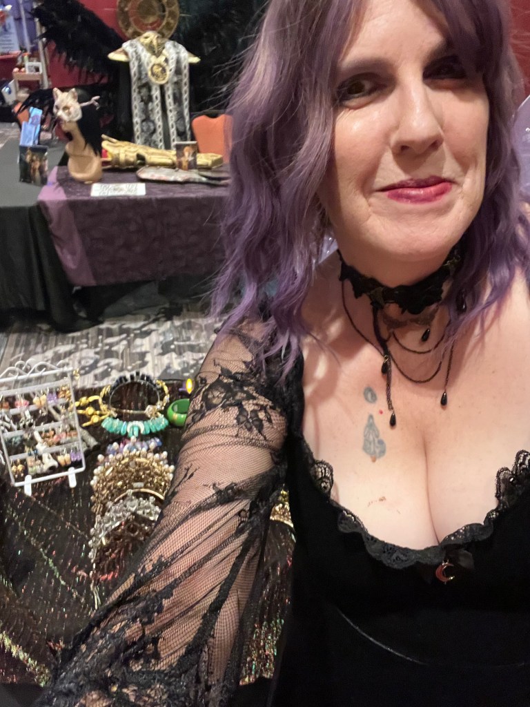 Woman in cosplay poses at a merch table