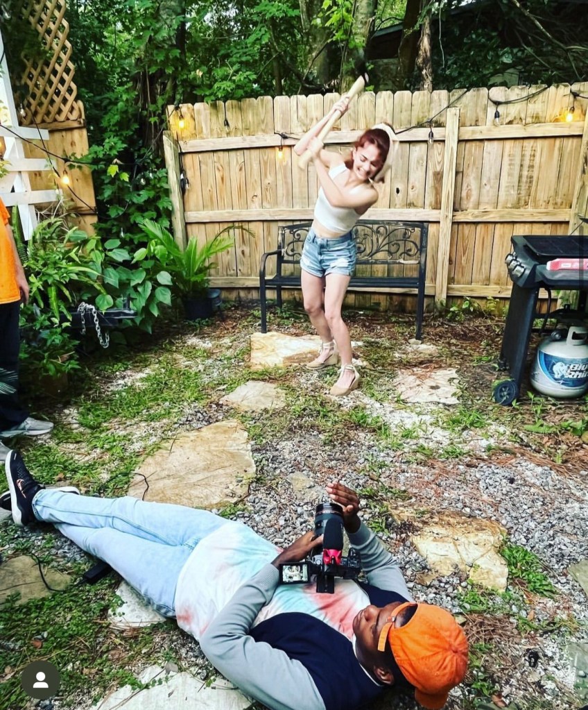Young woman pretends to swing an axe while being filmed